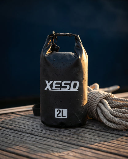 DryDock X-Series 2L Dry Bag in Black on a wooden boat dock at golden hour, alternate angle