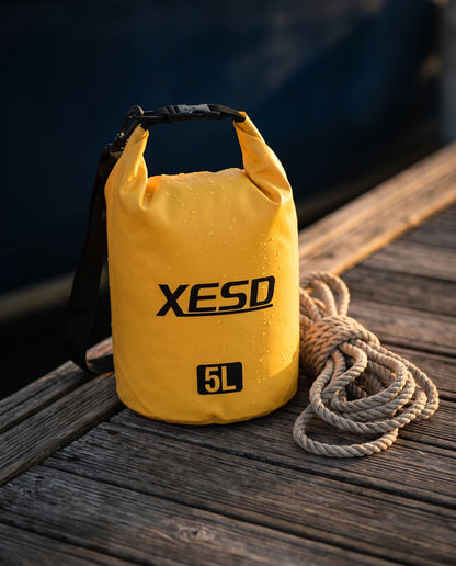 DryDock X-Series 5L Dry Bag in Yellow on a wooden boat dock at golden hour